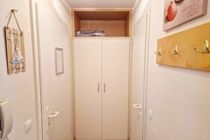 A narrow hallway with a wooden shelf at the top, a coat rack on the right, and a door with a handle on the left. - Charmante Ferienwohnung in Sellin mit Balkon (Sellin)