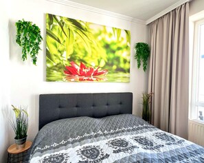 Ein Schlafzimmer mit einem Bett, einem großen Wandbild und zwei hängenden Pflanzen.