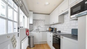 Een moderne keuken met witte kasten, een roestvrijstalen spoelbak, een Bosch magnetron en een oven.