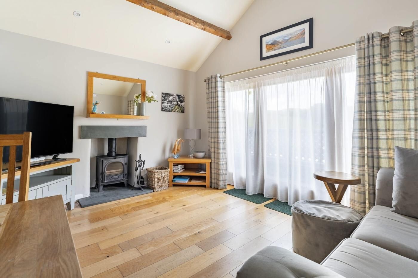 Ein gemütliches Wohnzimmer mit Kamin, Holzboden, einer Couch, einem Fernseher und einem Essbereich.