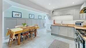 Una cocina moderna con comedor, que incluye estufa, microondas y armarios blancos.