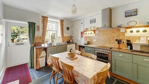 A kitchen with a dining table, chairs, a sink, a stove, and a window with curtains. - 3 Bed in Grasmere (oc-lr193) (Grasmere)