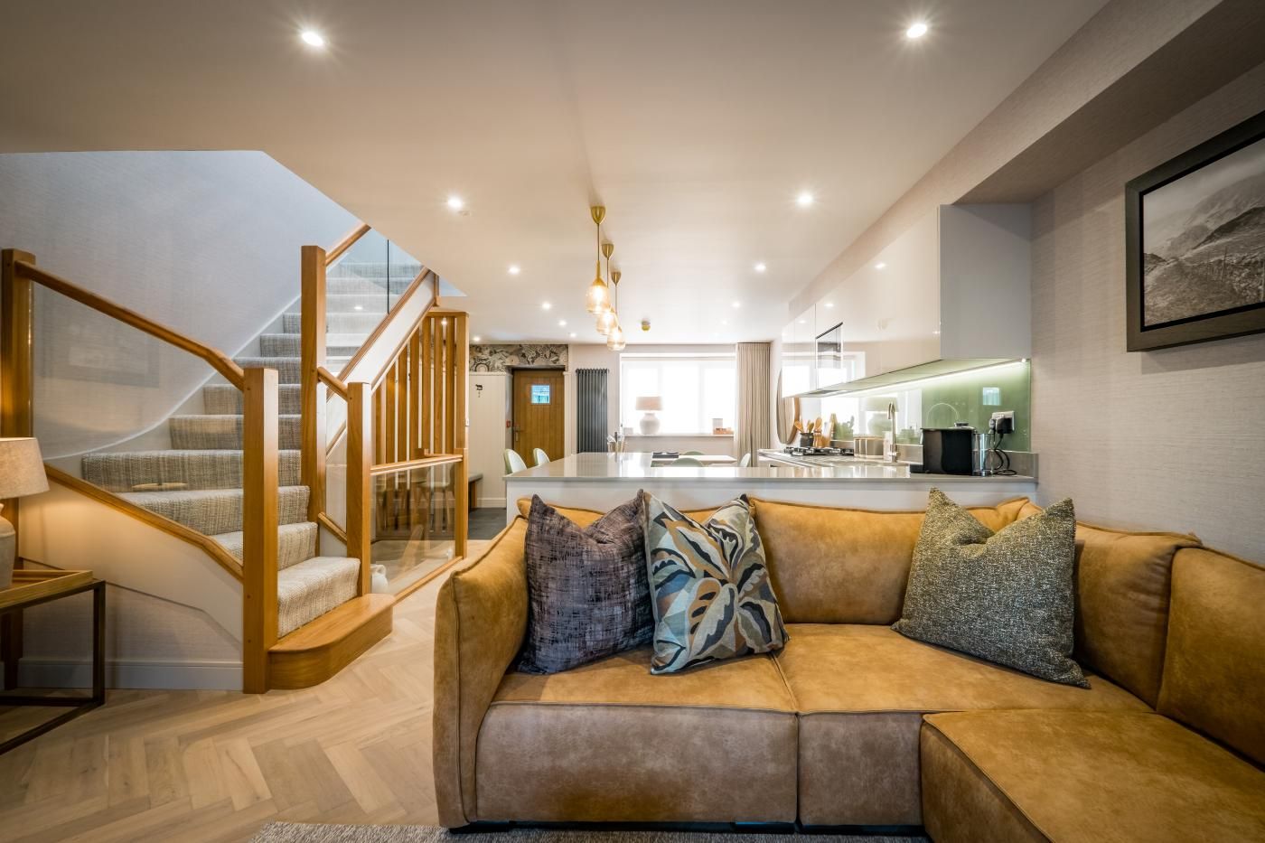 A modern interior with a staircase, a living area with a sofa, and a kitchen area.