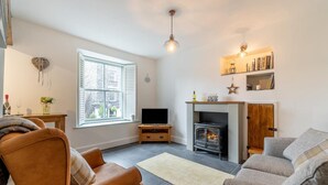 A living room with a fireplace, a television, and a sofa. - 1 Bed in Ambleside (oc-lr036) (Ambleside)