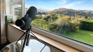 A telescope on a tripod by a window overlooking a landscape with hills and a lake. - 2 Bed in Ambleside (oc-lr191) (Ambleside)