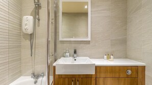 Een moderne badkamer met een douchecabine van glas, een wit wastafelmeubel en een houten opbergkast.