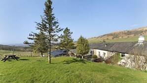 A rural setting with a stone house, a picnic table, and a large coniferous tree. - 1 Bed in Ambleside (oc-lr175) (Ambleside)