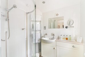 A modern bathroom with a glass shower enclosure, a sink with a mirror above it, and a cabinet below. - 7 Bed in Ambleside (oc-lr053) (Ambleside)