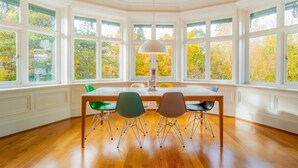 A dining area with a table and chairs, large windows, and a lamp. - 2 Bed in Ambleside (oc-lr218) (Claife)