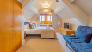 A bedroom with a bed, bedside table, TV, and a blue sofa. - 2 Bed in Ambleside (oc-lr218) (Claife)