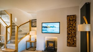 Eine Treppe mit Holzgeländern, ein an der Wand befestigter Fernseher, ein Kamin und eine Holzwand.