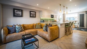 Ein modernes Wohnzimmer mit einer Couch, einem Couchtisch und einer Küche im Hintergrund.