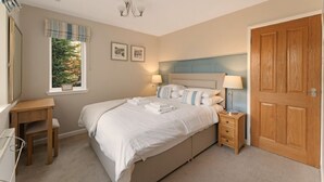 A bedroom with a bed, bedside tables, a desk, a wardrobe, and a window with curtains. - 4 Bed in Ambleside (oc-lr120) (Ambleside)