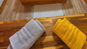 A bed with a wooden frame, two pillows, and a yellow blanket. - Tiny Ôm, water tank, and pools (Saint-François)