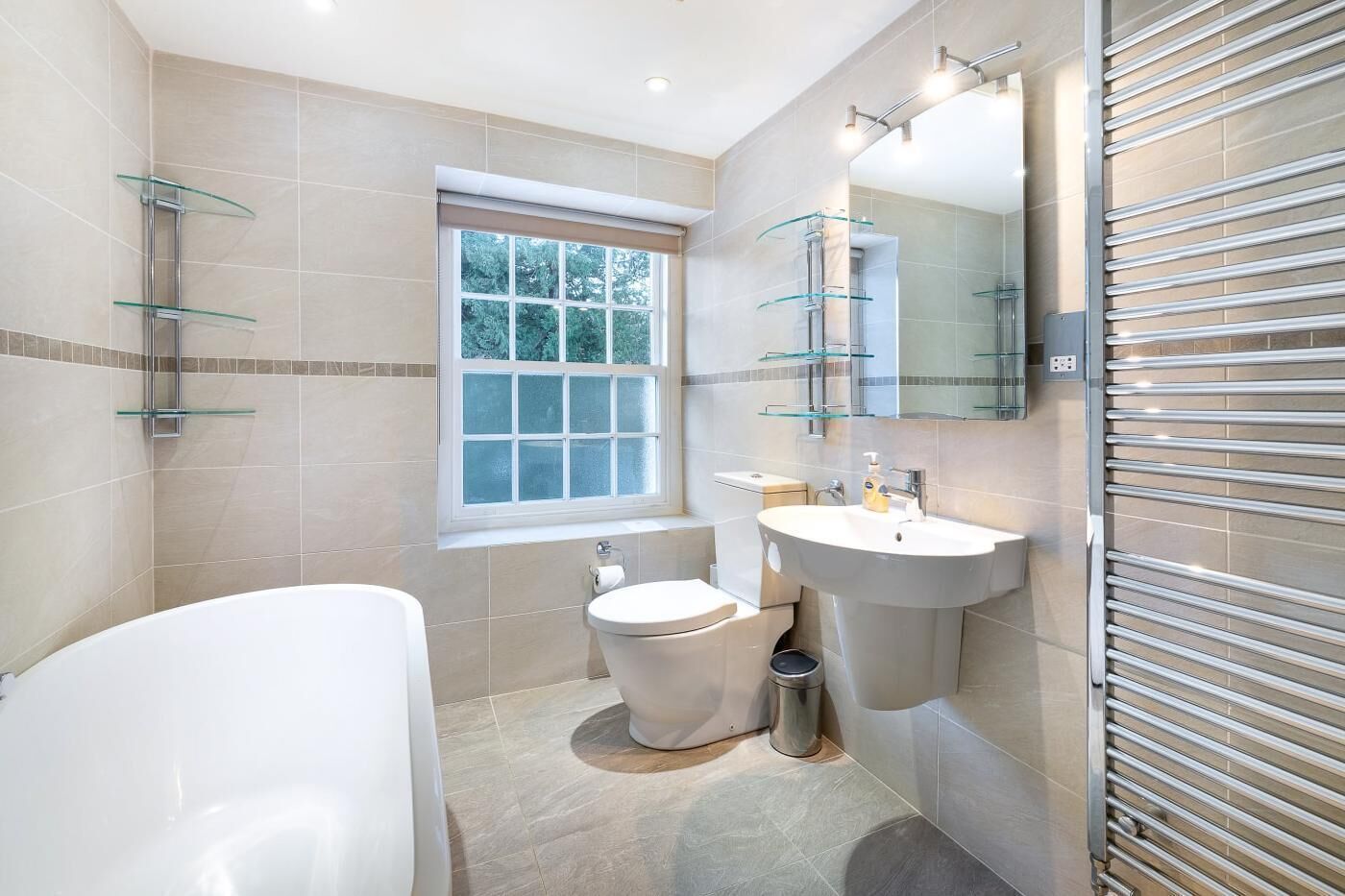 A modern bathroom with a bathtub, toilet, sink, and a window.