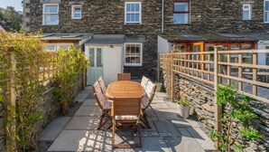 A stone building with a wooden table and chairs in the courtyard. - 3 Bed in Windermere (oc-lr044) (Windermere)