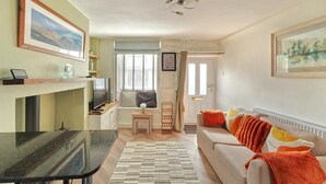 Un salon avec un canapé, une table basse, un téléviseur et une cheminée.