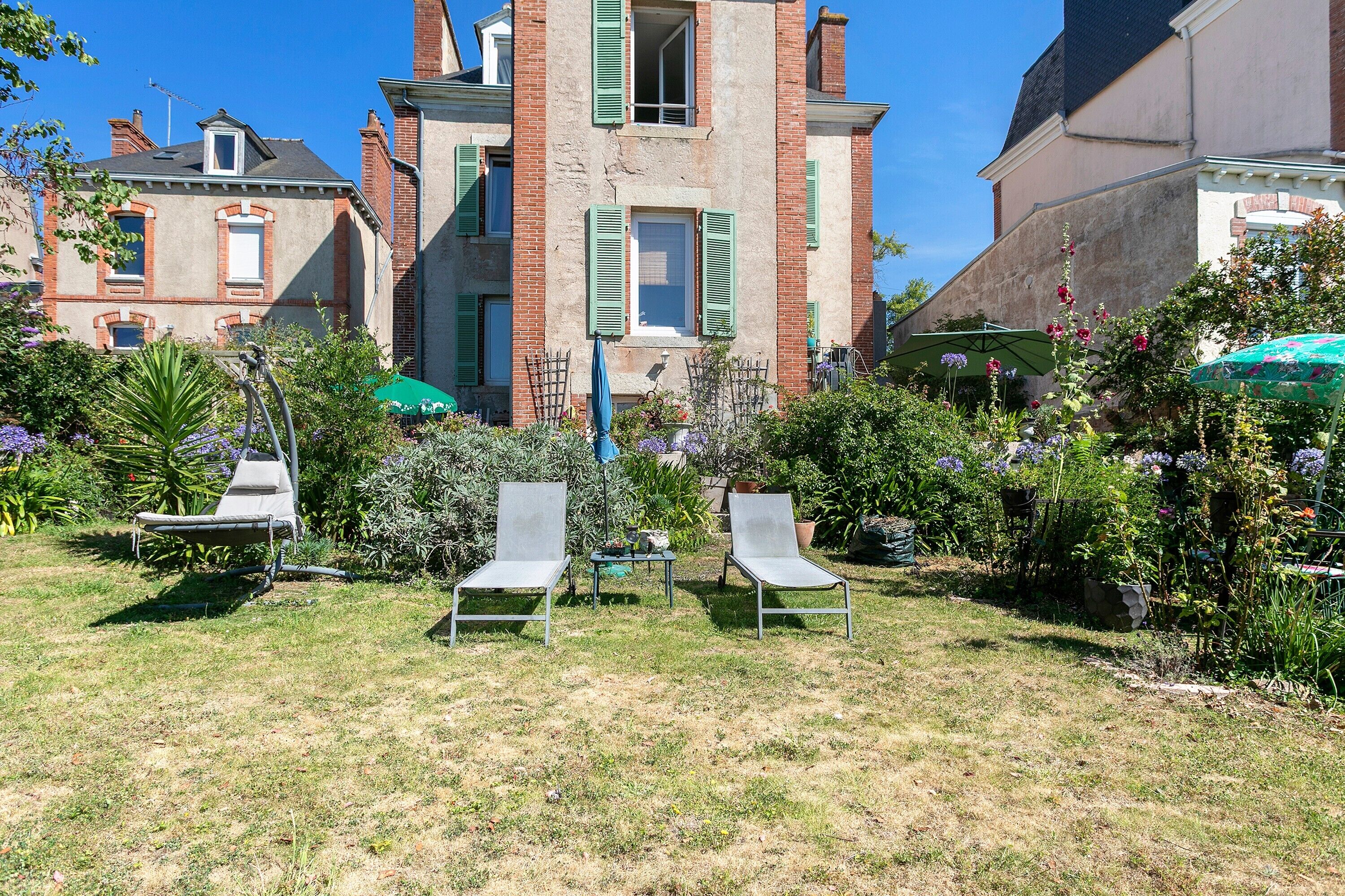 A courtyard with two lounge chairs, a small table, and a potted plant.