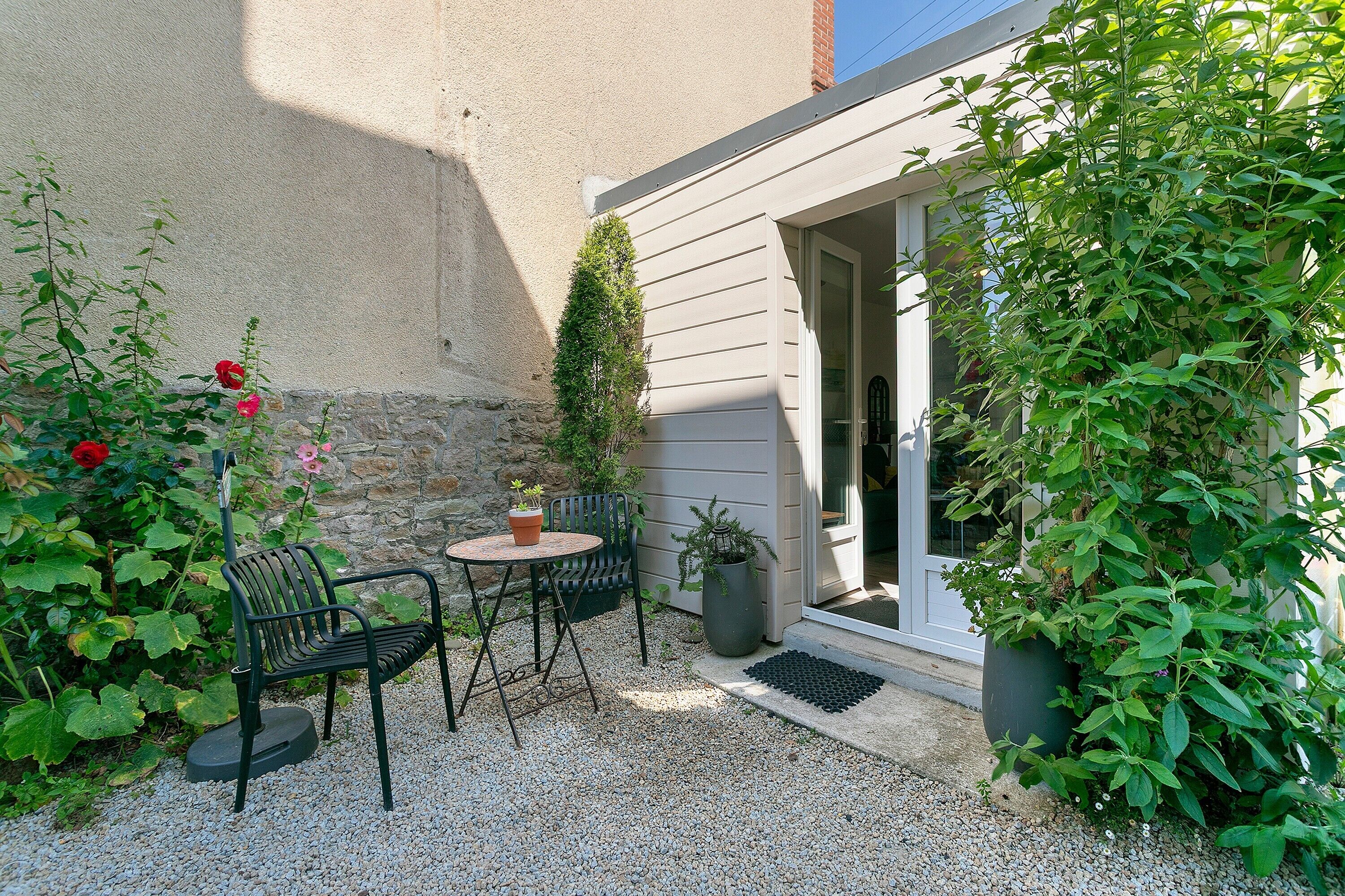 Un patio con tavolo e sedie, una pianta in vaso e una porta che dà su un edificio.