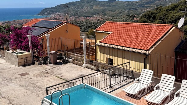 A swimming pool with a ladder, lounge chairs, and a view of the sea and hills. - Casa Lily 2: A Cozy Apartment with a View. (DIANO CASTELLO)