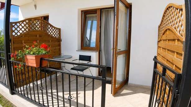 Ein Balkon mit Tisch und Stühlen, einem Blumentopf und einem Holztor.