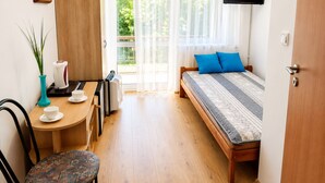 Ein Zimmer mit einem Bett, einem Schreibtisch, einem Stuhl, einem Fernseher und einem Fenster mit Vorhängen.