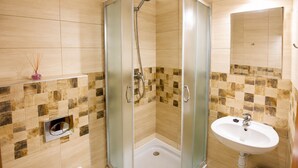 Ein Badezimmer mit einer Duschkabine, Toilette, Waschbecken und Spiegel.