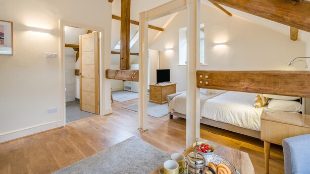 Ein Schlafzimmer mit Etagenbett, Holzboden, Schreibtisch mit Stuhl und kleinem Tisch mit Frühstücksangeboten.