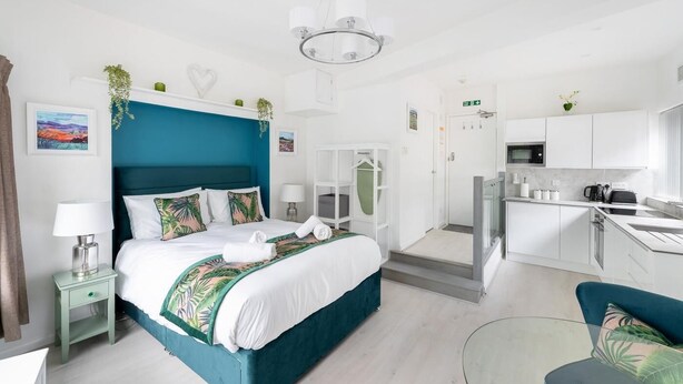 Ein modernes Hotelzimmer mit einem großen Bett, einer separaten Küchenzeile und Blick auf die Stadt.