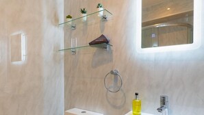 Ein modernes Badezimmer mit Toilette, Waschbecken und Glasregalen.