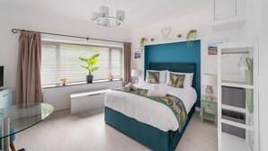 Ein modernes Schlafzimmer mit Bett, Nachttisch, Fenster mit Jalousien und einer Deckenleuchte.