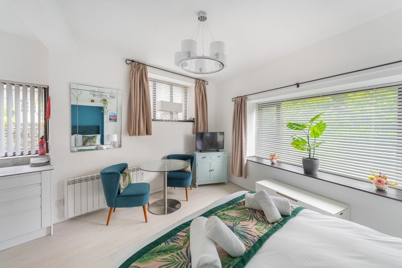 Een moderne hotelkamer met een bed, een bureau, een stoel, een televisie en een raam met zonwering.