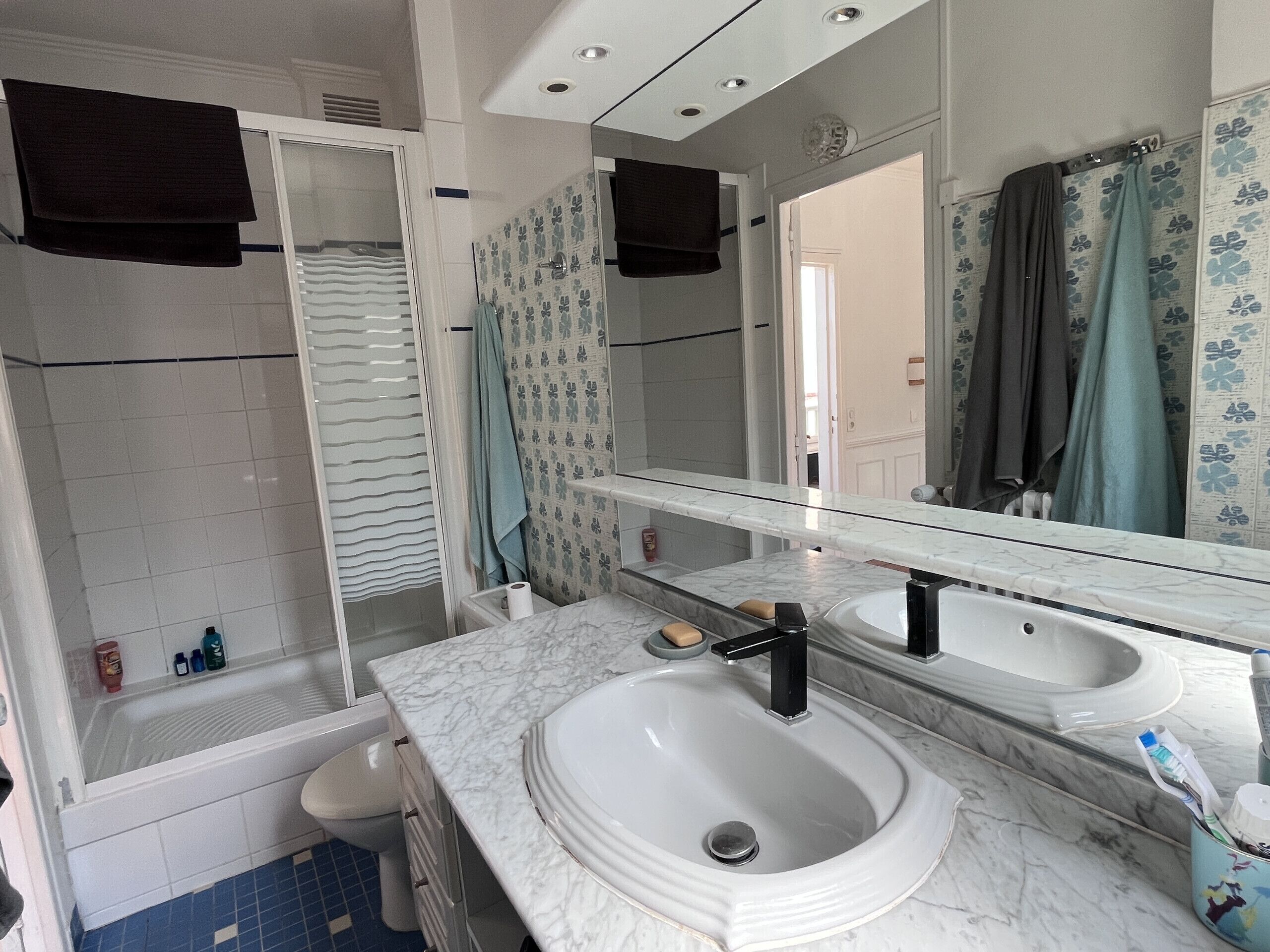 Une salle de bain avec une douche, deux lavabos, des toilettes et un miroir.