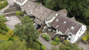 En traditionell byggnad i sten med flera våningar, en innergård och en parkeringsplats.