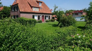 A two-story house with a red-tiled roof, a brick facade, and a well-maintained garden.
