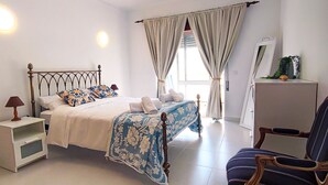 A bedroom with a bed, bedside tables, a chair, curtains, and a desk. - Apartment 'Casa Várzea' with Wi-Fi (Lagos)