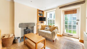 A cozy living room with a fireplace, a sofa, a TV, and a bookshelf. - 2 Bed in Ambleside (oc-lr166) (Ambleside)