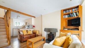 A living room with a sofa, a coffee table, a fireplace, a television, and a bookshelf. - 2 Bed in Ambleside (oc-lr166) (Ambleside)
