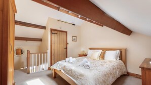 A bedroom with a wooden bed, a nightstand, a lamp, and a door leading to another room. - 2 Bed in Ambleside (oc-lr166) (Ambleside)