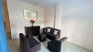 A modern living room with a sofa set, a small table with a vase of flowers, and a decorative mirror on the wall. - NCG Suite 2 (Guayaquil)