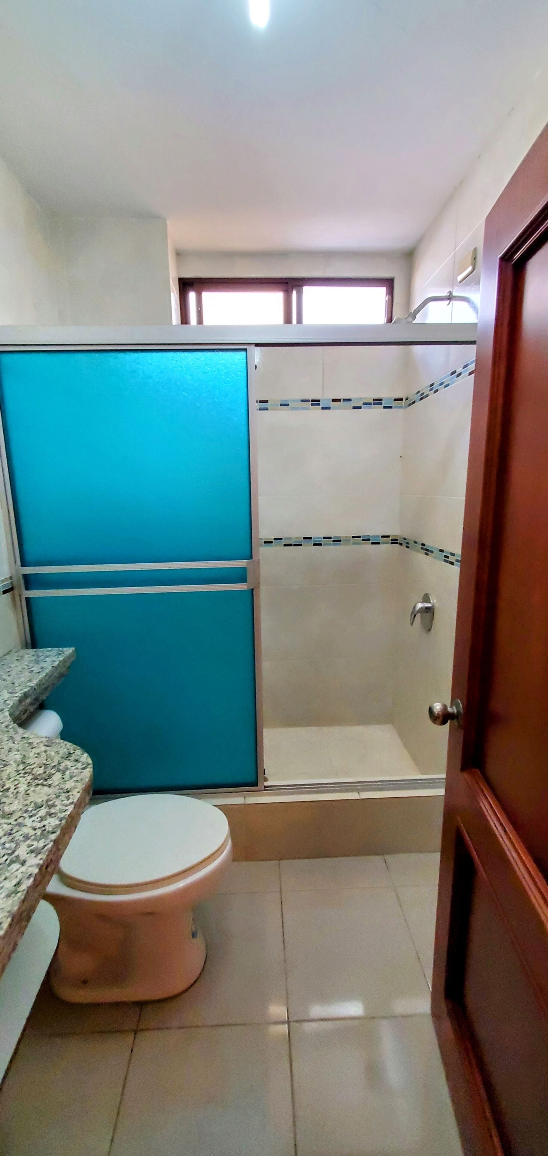 A bathroom with a toilet, a shower stall, and a sink.