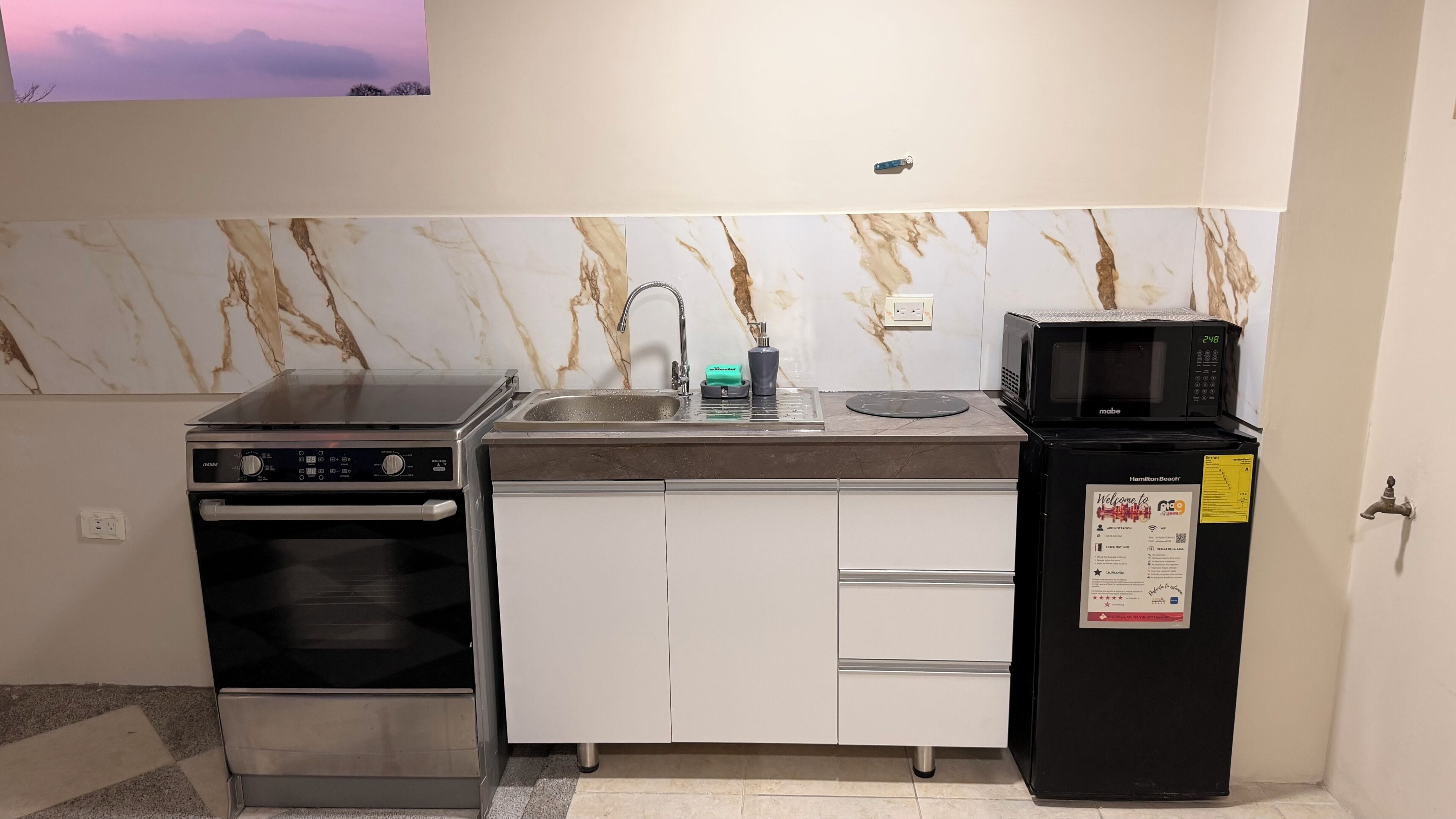 A compact kitchen with a built-in oven, a microwave, and a sink.