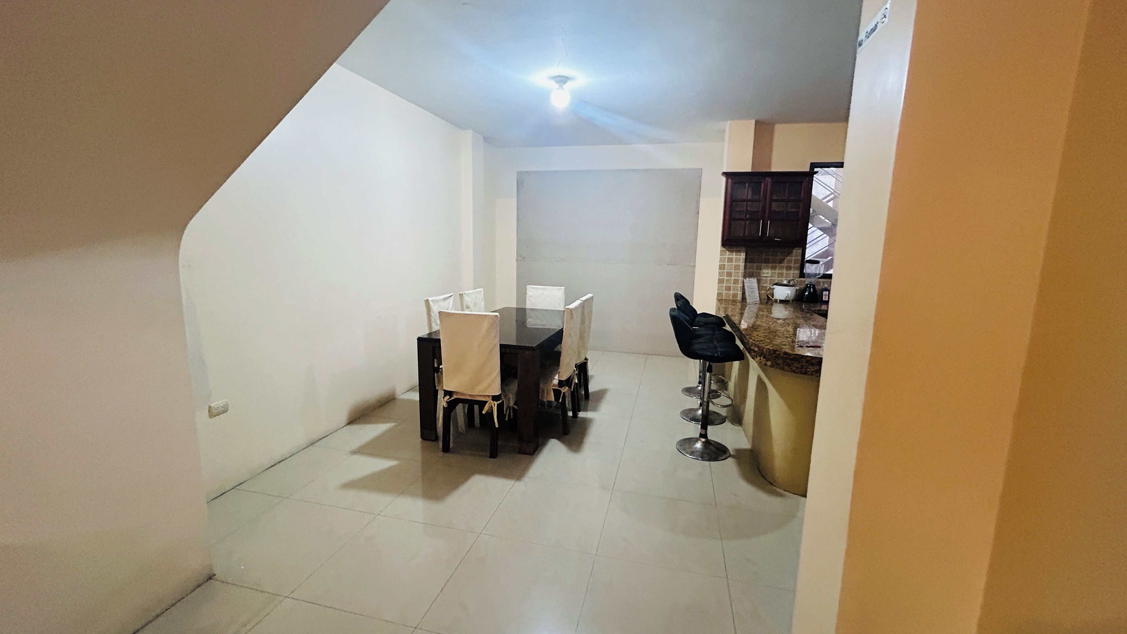 Comedor con mesa y sillas, zona de cocina con armarios y encimera, y ventilador de techo.