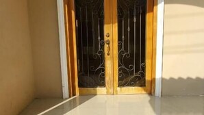 A closed wooden door with a decorative metal gate, a white arch above it, and a plain wall. - NCG Suite 2 (Guayaquil)