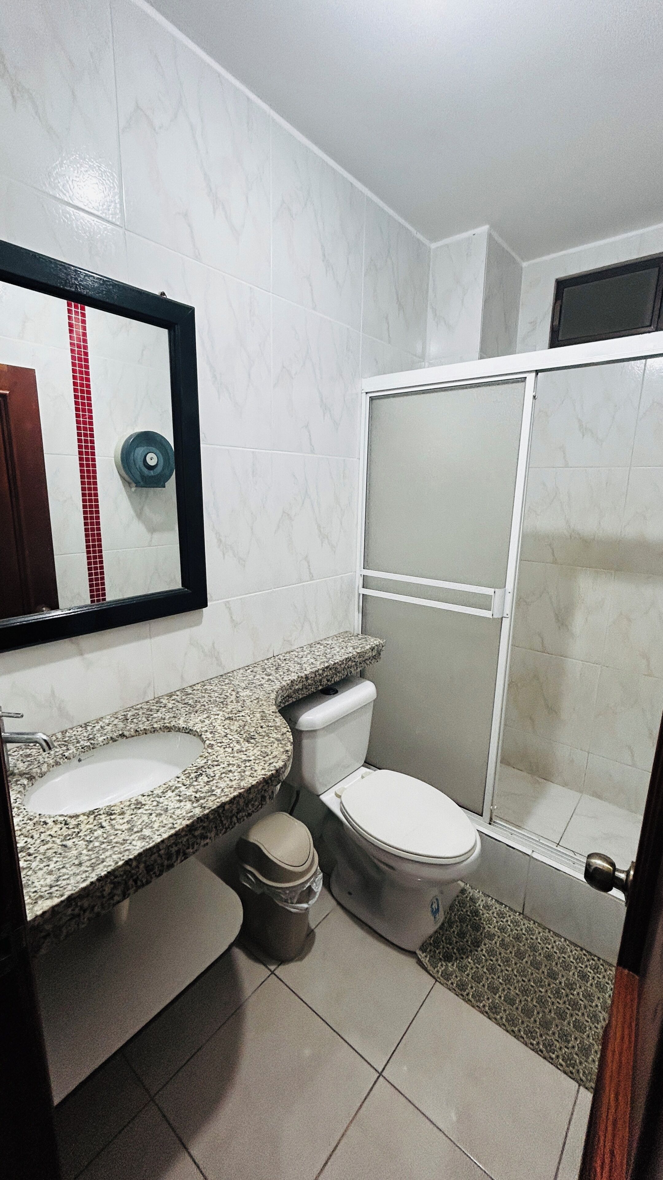 Un baño con tocador de mármol, inodoro, cabina de ducha y espejo.