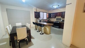 A kitchen with a dining area, including a table with chairs, a bar counter, and a stove. - NCG Suite 2 (Guayaquil)