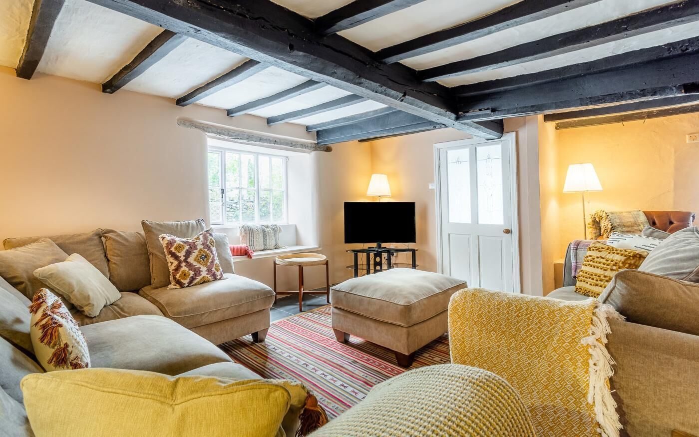 A cozy living room with a sofa set, a television, and a lamp.