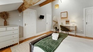 Quarto com cama, penteadeira, escrivaninha, cadeira, espelho e luminária pendente.