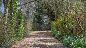Un chemin de gravier bordé d’une végétation luxuriante et d’arbres.
