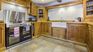 Una cucina con mobili in legno, piano cottura in acciaio inossidabile e pavimento in pietra.